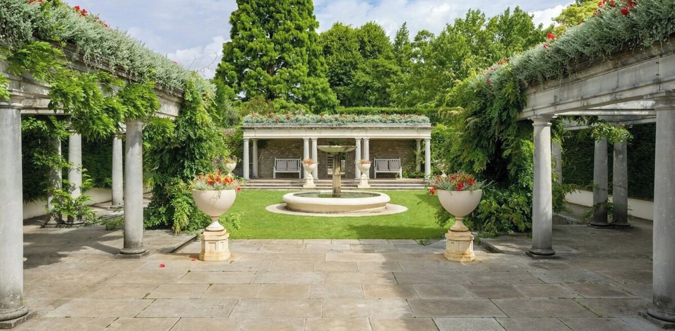 A courtyard with a fountain, columns, and a covered structure.