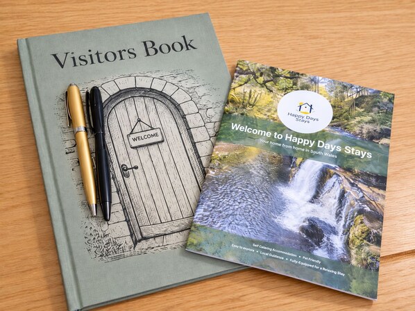 A visitors book and a welcome brochure for Happy Days Stays in South Wales. - Modern, light-filled townhouse with a king bed, spacious living room with an electric fireplace, fully equipped kitchen, dedicated workspace, and free on-site parking for one car. Enjoy a private outdoor patio . (Bridgend County Borough)