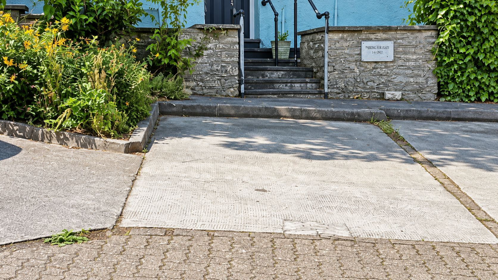 Ein Parkplatz mit einer Steinmauer und einem Schild, das Parkplätze ausschließlich für Wohnungen J-6 ausweist.