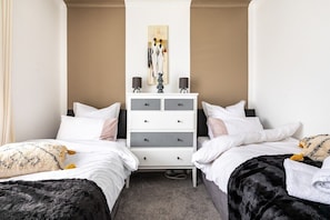 Ein Hotelzimmer mit zwei Betten, einer weißen Kommode und einem Gemälde an der Wand.