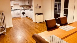 Una cocina compacta con armarios blancos, lavadora y comedor con mesa y sillas.