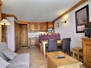 A cozy kitchen with wooden cabinets, a tiled backsplash, and a dining area with a table and chairs.