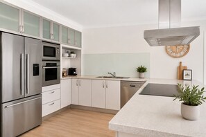 A modern kitchen with stainless steel appliances, white cabinetry, and a central island. - La Maison Ver La Mer by Ready Set Stay - Big & Beautiful Backyard (Rye)