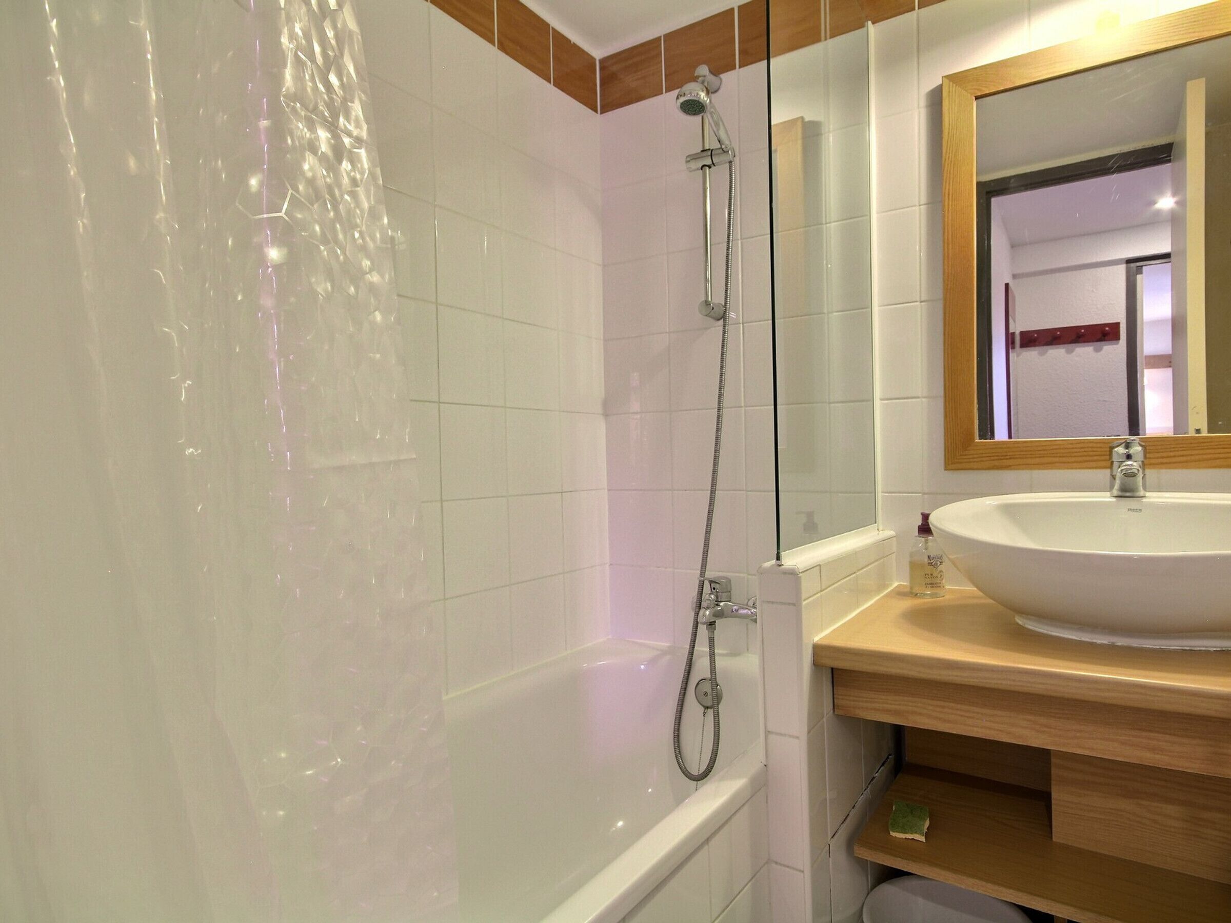 A bathroom with a bathtub, a shower, and a sink with a mirror above it.