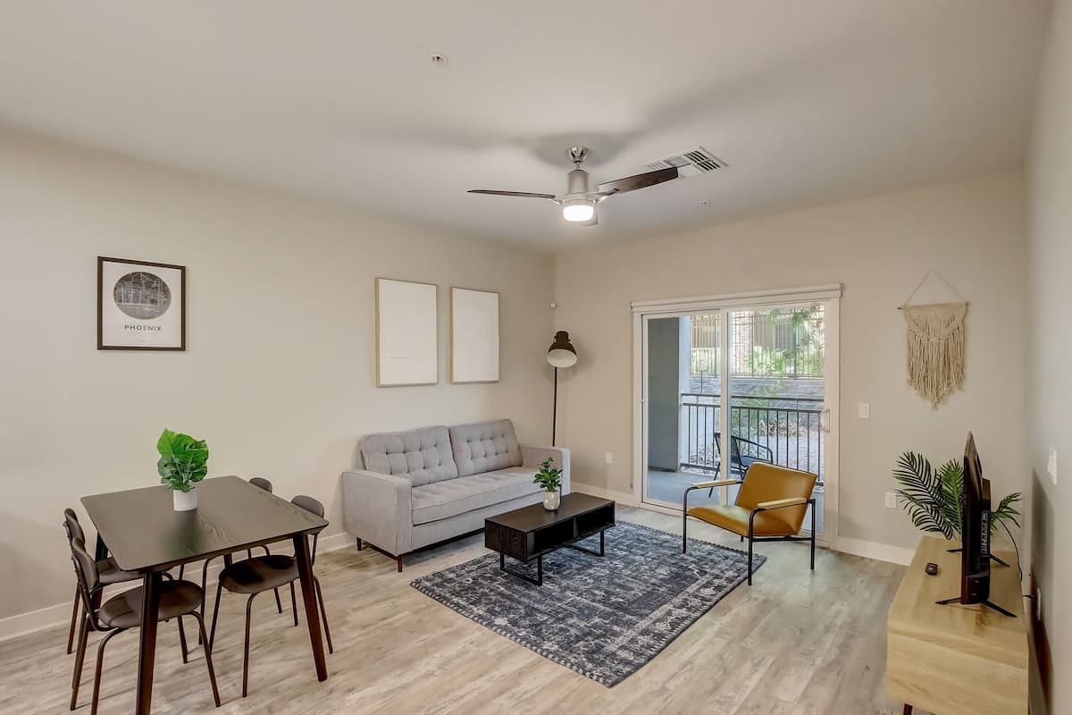 A living room with a dining table, sofa, and a ceiling fan.
