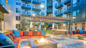 Ein Außenbereich mit einer Terrasse, einem Feuerkorb, Sitzgelegenheiten und einer Pergola.