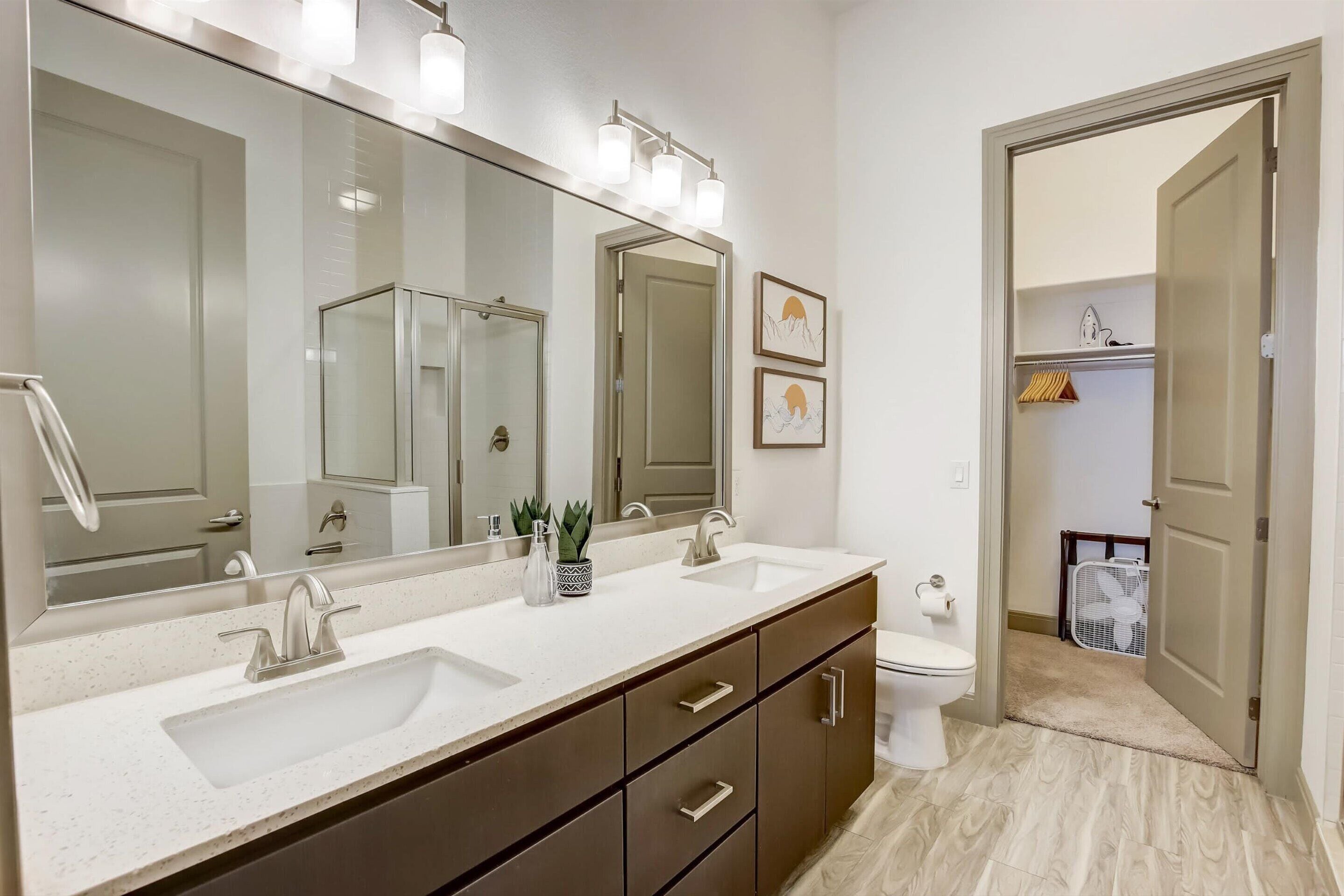 A bathroom with a double sink, large mirror, and a walk-in closet.