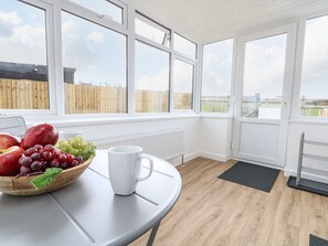 A kitchen with a round table, a bowl of fruit, and a white mug. - Cliff Barn (Bridport)