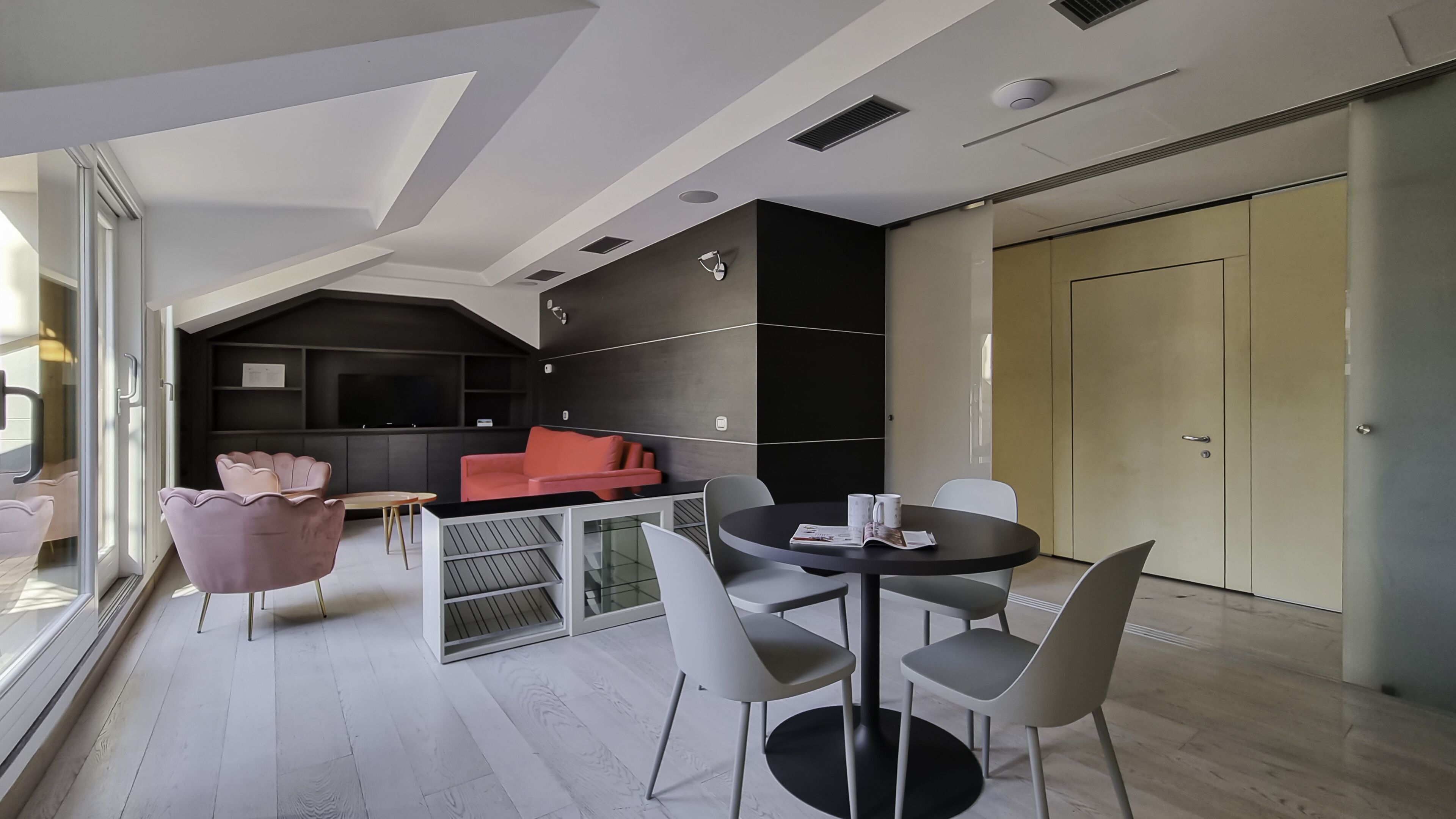 Un intérieur moderne comprenant un coin repas, un espace de vie avec un canapé rouge et un mur d’accent noir.