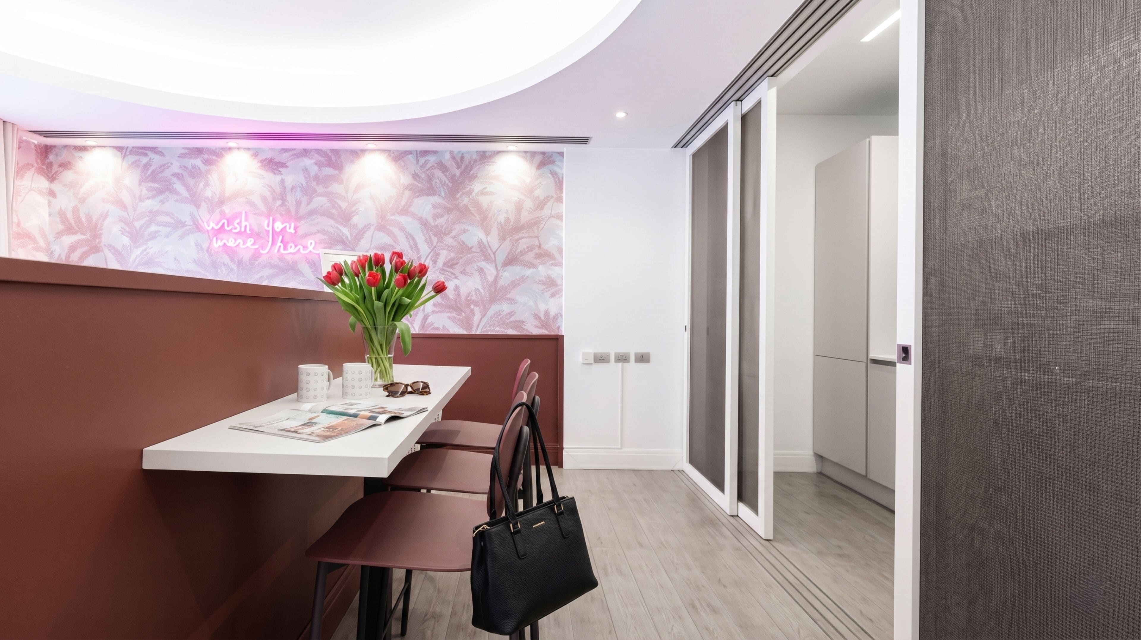 A reception desk with a vase of red tulips, a magazine, and a black handbag.