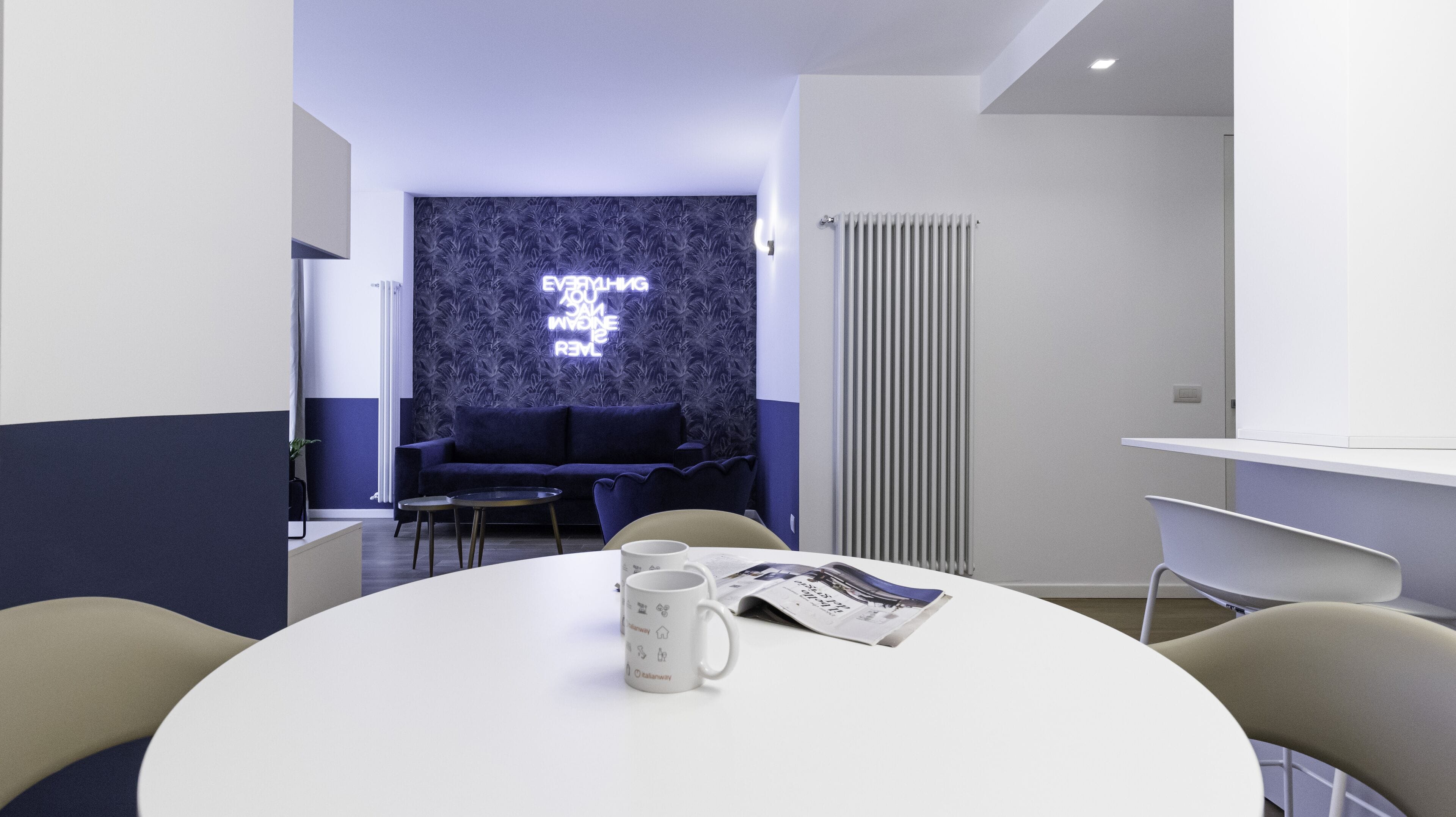 Ein modernes Zimmer mit rundem Tisch, zwei Stühlen, einer Schlafcouch und einer Heizung.