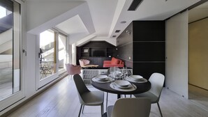A modern dining area with a round table set for four, a kitchen in the background, and a view of a balcony. - Italianway - Corso Venezia 7 (Milan)