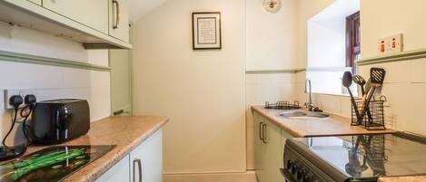 A compact kitchen with a gas stove, a toaster, and a sink.