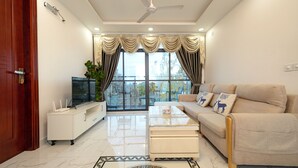 Una sala de estar moderna con sofá, mesa de centro, televisor y vistas amplias por las ventanas.
