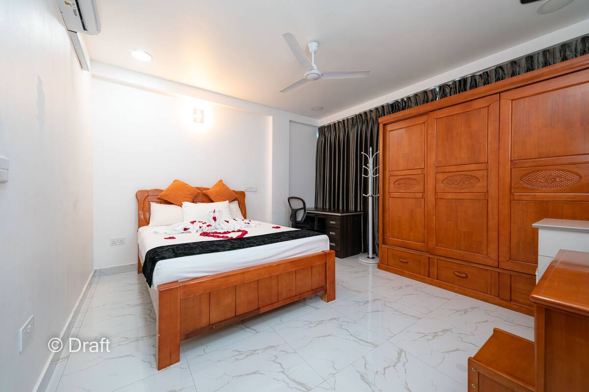 A bedroom with a wooden bed, a wardrobe, a desk, and a ceiling fan.