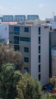 Un edificio de varios pisos con un diseño arquitectónico moderno, que combina fachadas de vidrio y concreto.