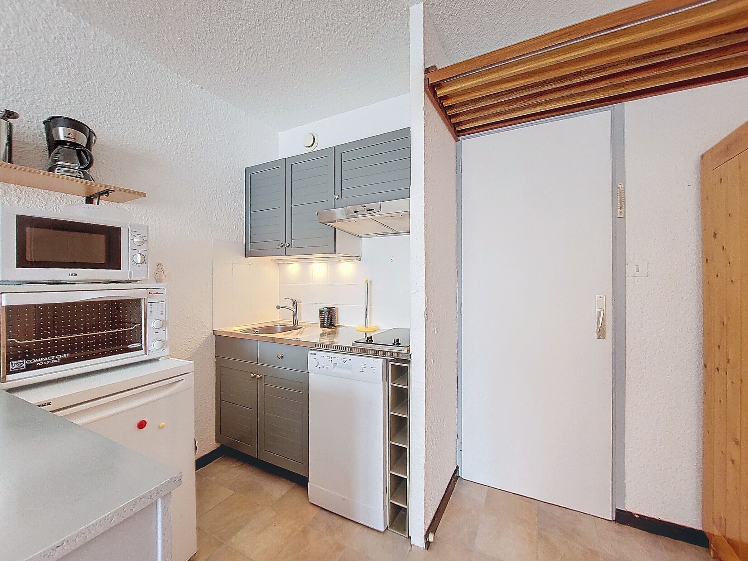 Eine kompakte Küche mit Mikrowelle, Toaster und Geschirrspüler.