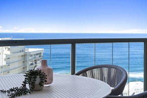 Enjoy the ocean view from this balcony with a round table and wicker chair.