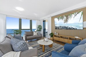 Enjoy the ocean view from the comfort of this spacious living room with a sofa set, coffee table, and TV.