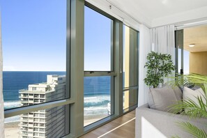 Enjoy ocean views from the large window in this stylish living room with a comfortable sofa and potted plant.