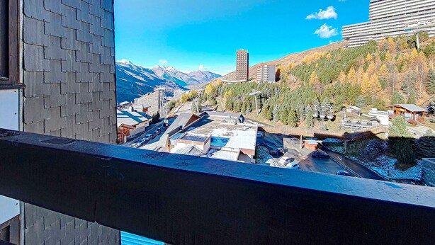 A view from a balcony overlooking a mountainous area with buildings and a ski lift. - Renovated Studio 3 pers. - Ski-in Ski-out with Balcony (Les Menuires)