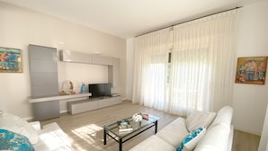 A modern living room with a sofa, coffee table, TV, and artwork on the walls. - Lakefront villa with secular park, private jetty and pool 10 km from Salò (Toscolano Maderno)