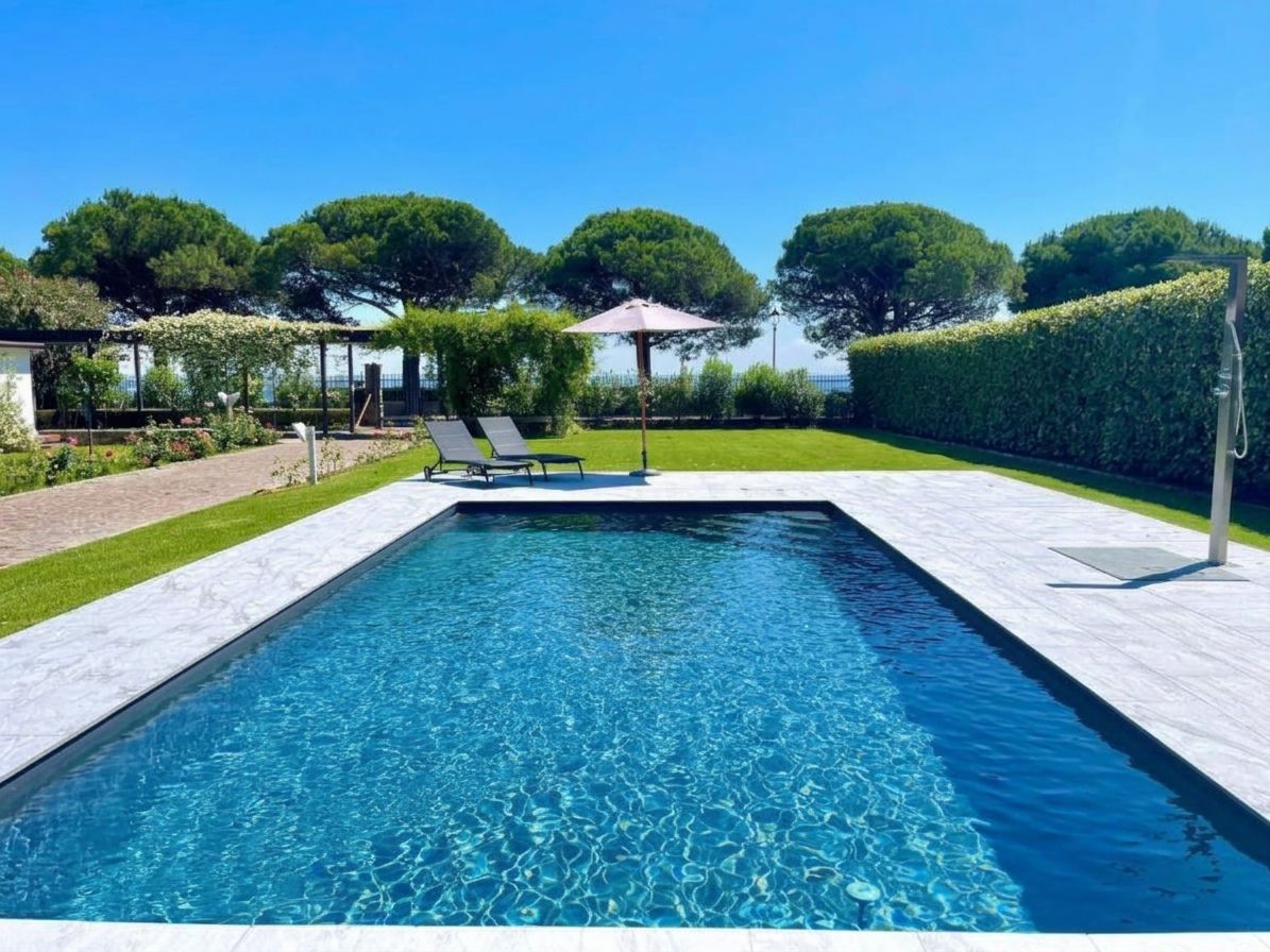 A rectangular swimming pool with clear blue water, surrounded by a tiled deck.