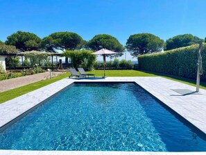 Une piscine rectangulaire à l’eau d’un bleu limpide, entourée d’une terrasse carrelée.