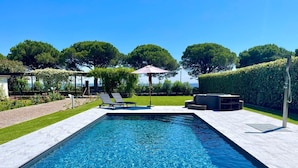 A rectangular swimming pool with clear blue water, surrounded by a paved deck. There are two lounge chairs and a covered seating area. - Lakefront villa with secular park, private jetty and pool 10 km from Salò (Toscolano Maderno)