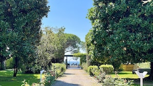 A cobblestone pathway flanked by lush greenery and a clear blue sky. - Lakefront villa with secular park, private jetty and pool 10 km from Salò (Toscolano Maderno)