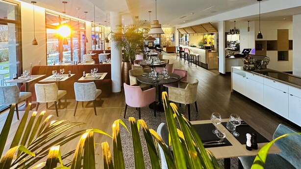 A modern hotel lobby with a bar, seating areas, and a kitchen in the background. - Courrier Sud (Quint-Fonsegrives)