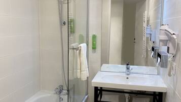 Une salle de bain moderne avec une douche à parois de verre, un lavabo blanc doté d’un cadre noir et un miroir au-dessus du lavabo.