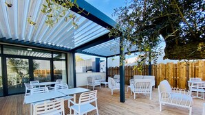 An outdoor patio with white furniture, a wooden deck, and a view of the surrounding area. - Courrier Sud (Quint-Fonsegrives)