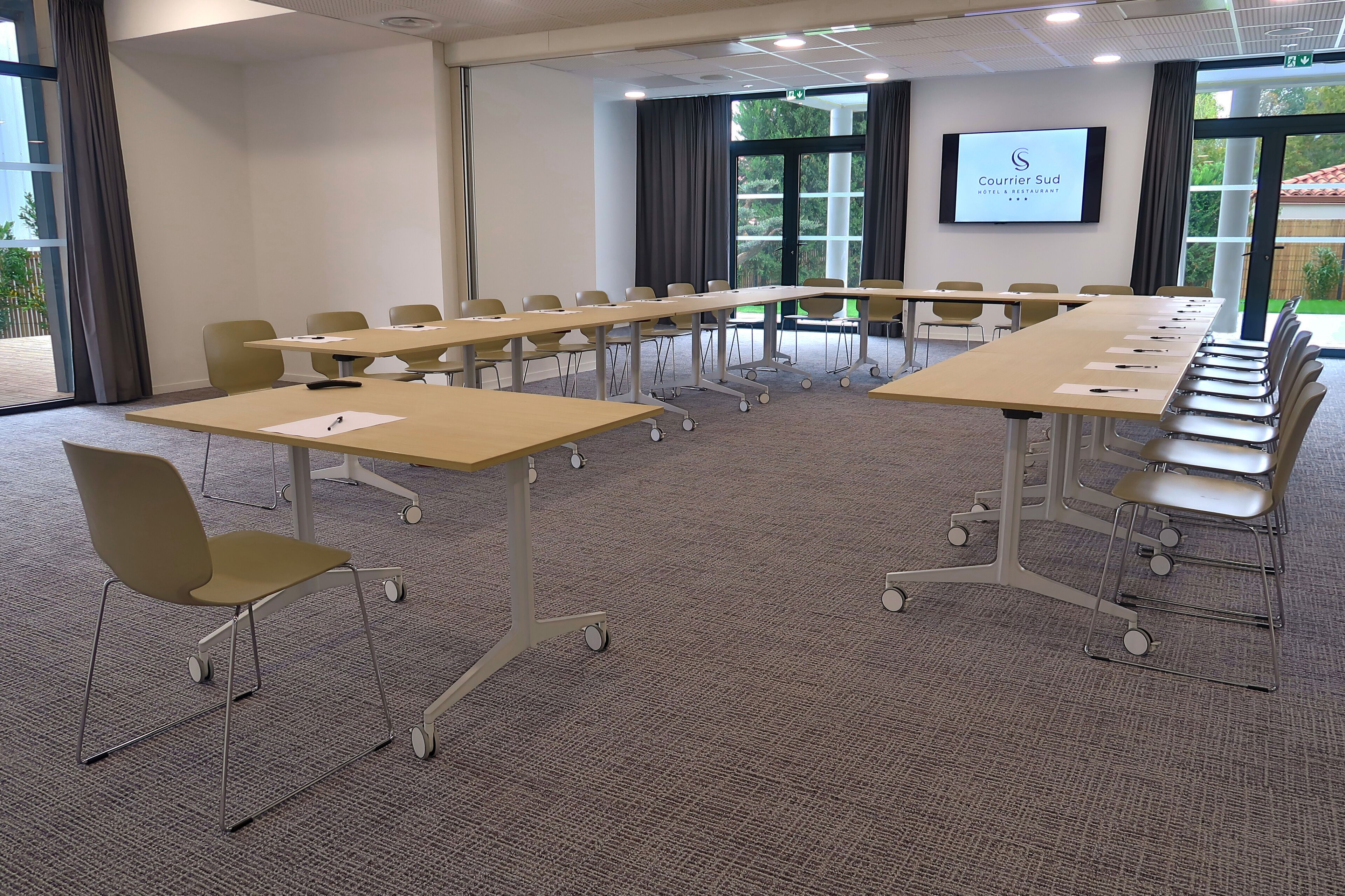 A conference room with a long table, chairs, and a presentation screen.