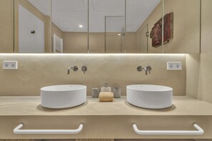Ein modernes Badezimmer mit zwei runden Waschbecken, einem Spiegel und einem Handtuchhalter.