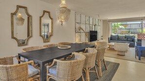 A dining area with a dark table, wicker chairs, and a chandelier. - Casa Bambu - Marbellamar (Marbella)