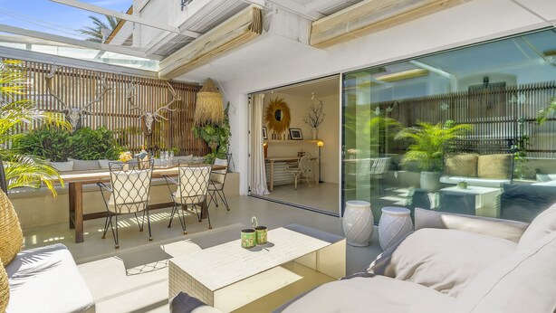 A modern outdoor patio with a dining area, seating, and a glass wall. - Casa Bambu - Marbellamar (Marbella)