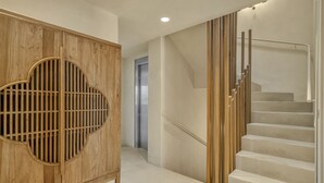 A modern interior with a wooden cabinet, a staircase, and a hallway leading to a door. - Casa Bambu - Marbellamar (Marbella)