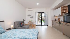 Quarto de hotel moderno com uma cama, um sofá, área de refeições e cozinha.