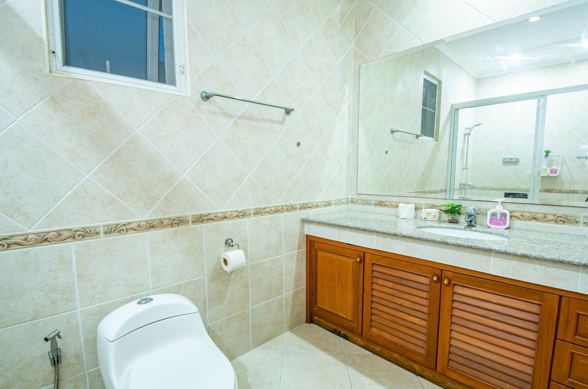 A bathroom with a toilet, sink, mirror, and shower area.