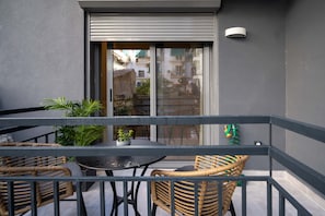Un balcon agrémenté de meubles en osier, d’une table et de plantes en pot.