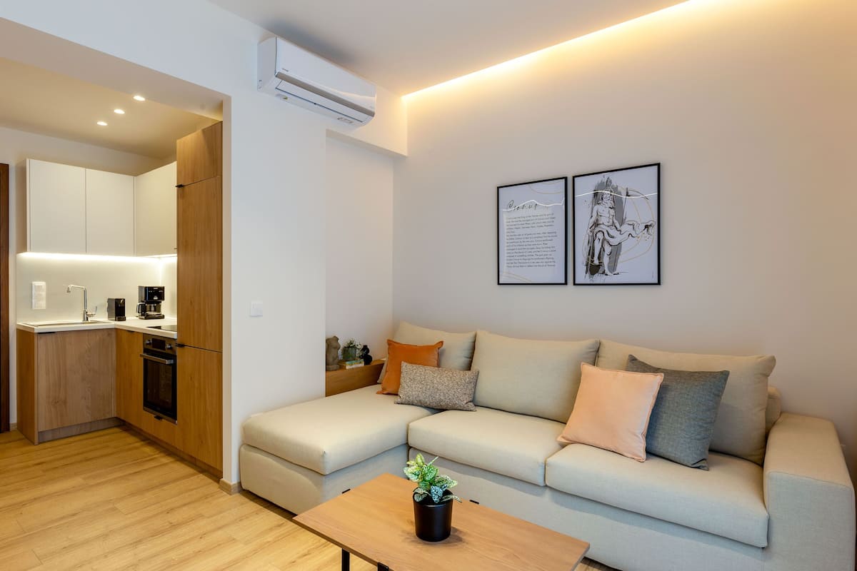 A modern living room with a sofa, a coffee table, and a kitchen in the background.