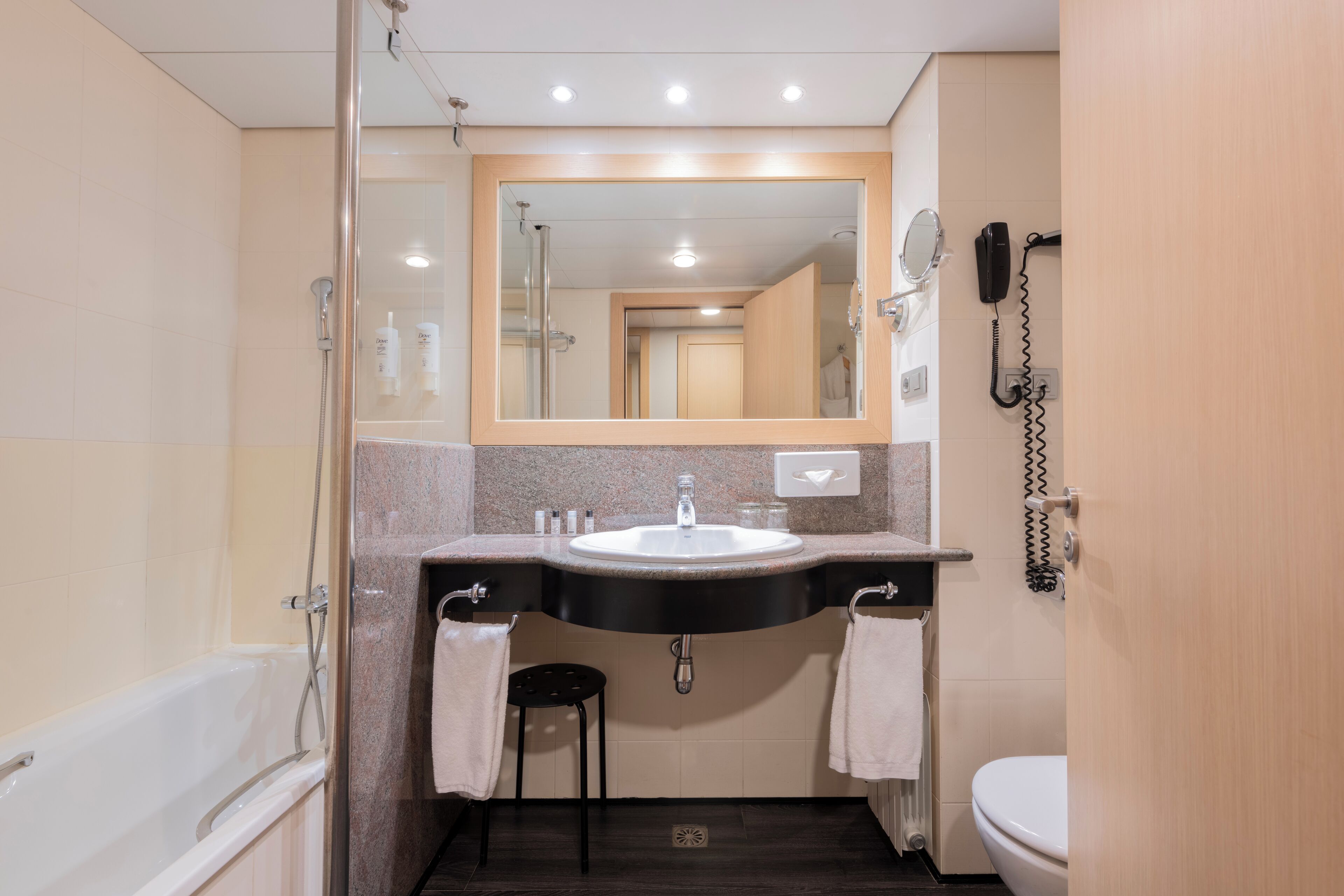 Un baño moderno con bañera, lavabo, inodoro y espejo.