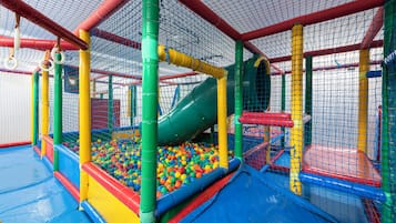 An indoor play area with a slide, ball pit, and safety netting.