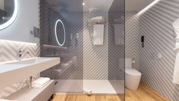A modern bathroom with a glass-enclosed shower, a vanity with a mirror, and a toilet.
