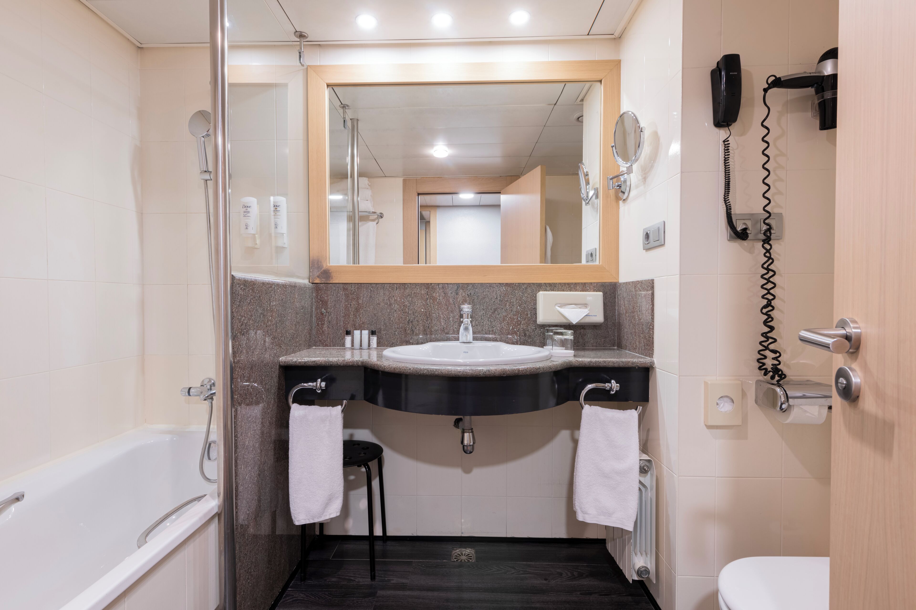 A modern bathroom with a bathtub, a sink with a mirror above it, and a toilet.