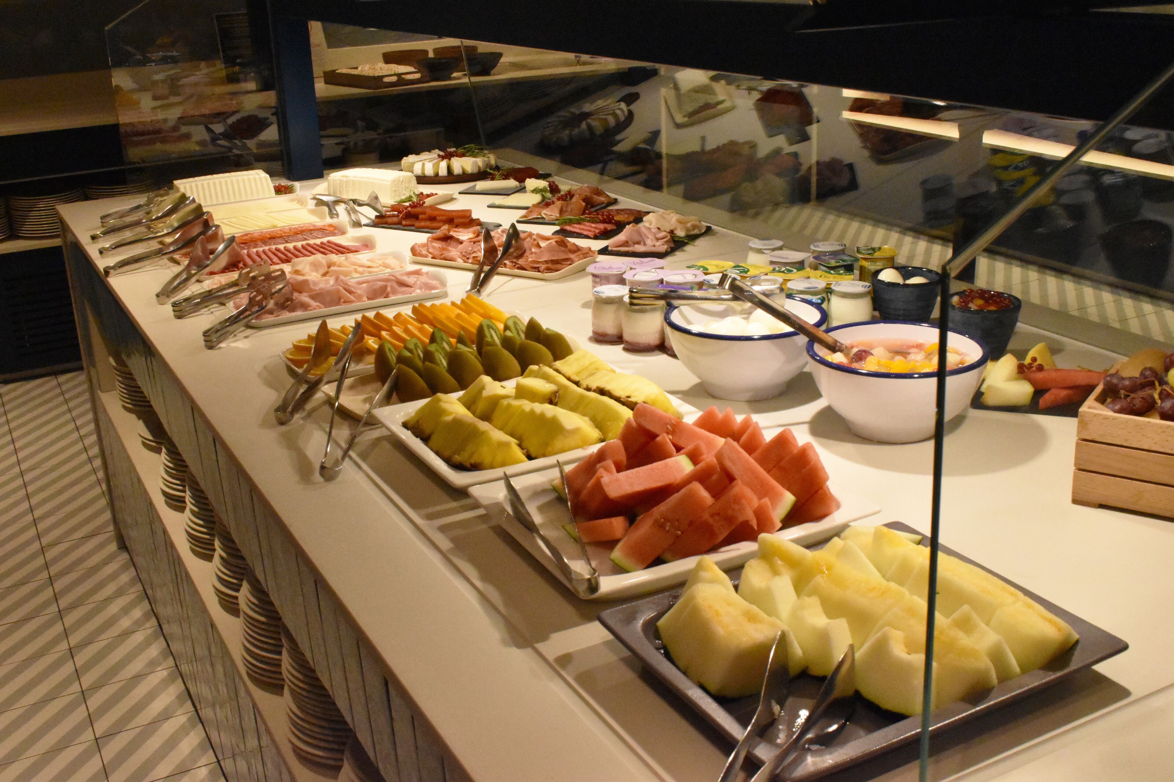A buffet with various food items including fruits, cheeses, and meats.