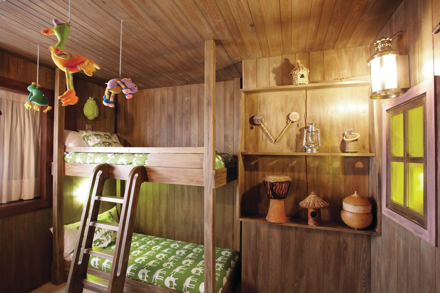 Ein rustikaler Holzraum mit einem Stockbett, einer Himmelsleiter und Regalen mit verschiedenen Gegenständen, darunter eine Laterne, eine Trommel und ein Korb.