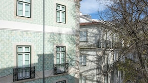 Un edificio de varios pisos con fachada de tejas, múltiples ventanas y un balcón con barandilla de hierro forjado.