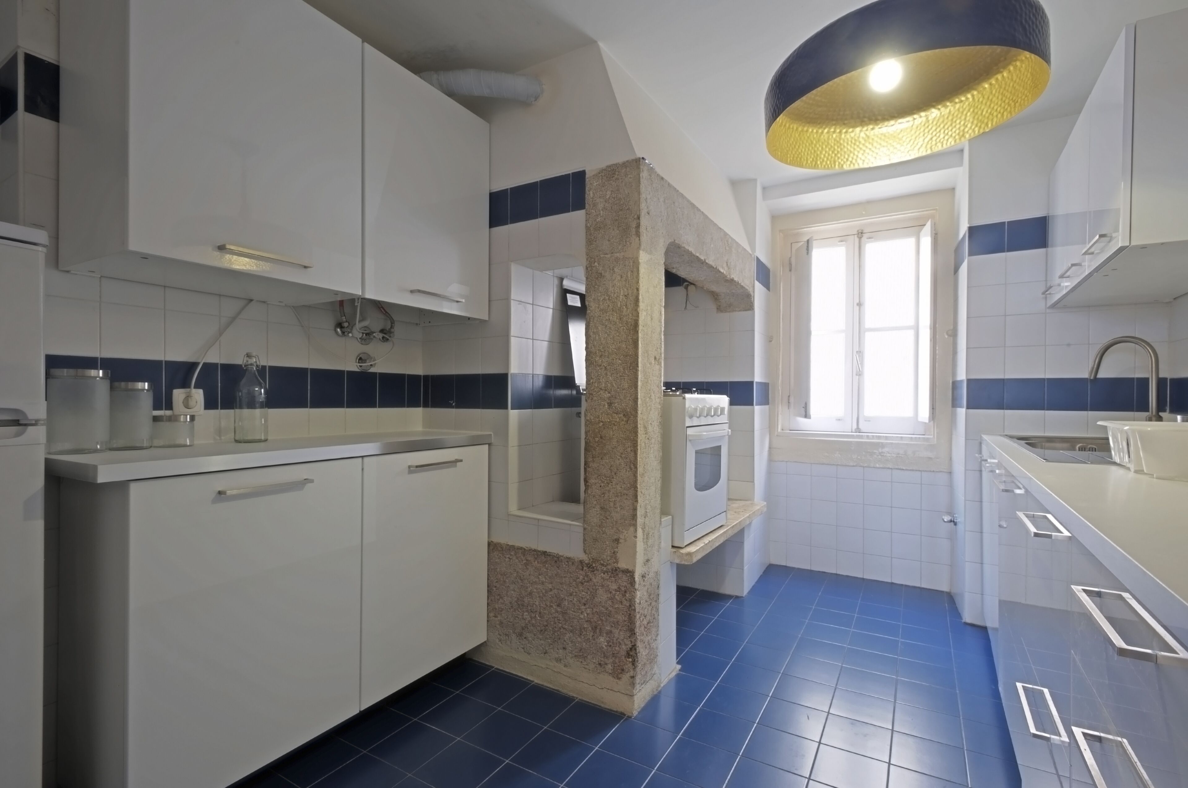 A modern kitchen with white cabinets, a built-in oven, and a blue-tiled backsplash.